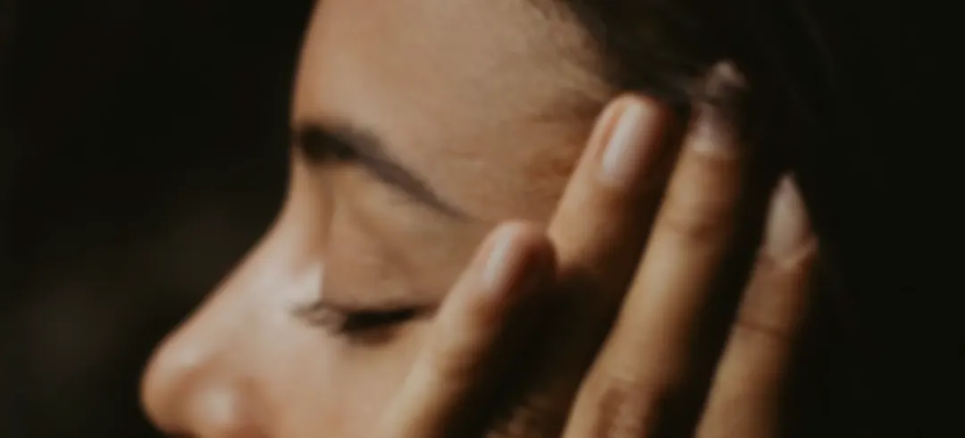 Mujer con los ojos cerrados y la mano en el rostro